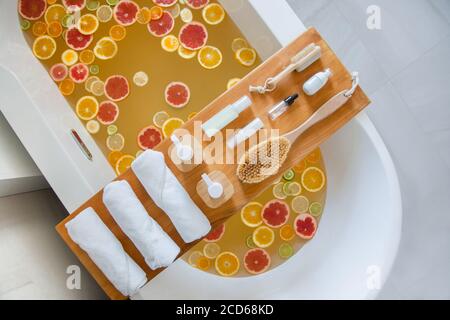 Badewanne mit gemischten Scheiben von frischen Zitrusfrüchten und Spa-Set aus Naturprodukten. Stockfoto