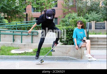 (200827) -- PEKING, 27. August 2020 (Xinhua) -- Lin Ziyis Mutter sieht zu, wie Lin (L) in ihrer Wohngemeinschaft in Peking, der Hauptstadt von China, Skateboarding praktiziert, 8. August 2020. Der 16-jährige Lin Ziyi ist Schüler der Pekinger Hochschule Nr. 4. Sie hat sich vor vier Jahren in Skateboarding verliebt, als ihr Vater ihr ein Skateboard zum Geburtstag schenkte. Danach wurde sie süchtig nach dem Sport. Als sie gefragt wurde, wie es sich beim Skateboarden anfühlte, sagte sie: "Du denkst an nichts und es fühlt sich an wie Fliegen." Aber es hat nicht immer Spaß gemacht. Ihre Beine wurden schwarz und blau, nachdem sie vom Skateboard tim gefallen waren Stockfoto