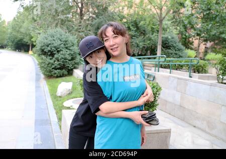 (200827) -- PEKING, 27. August 2020 (Xinhua) -- Lin Ziyi (L) posiert mit ihrer Mutter für Fotografie in ihrer Wohngemeinschaft in Peking, Hauptstadt von China, 8. August 2020. Der 16-jährige Lin Ziyi ist Schüler der Pekinger Hochschule Nr. 4. Sie hat sich vor vier Jahren in Skateboarding verliebt, als ihr Vater ihr ein Skateboard zum Geburtstag schenkte. Danach wurde sie süchtig nach dem Sport. Als sie gefragt wurde, wie es sich beim Skateboarden anfühlte, sagte sie: "Du denkst an nichts und es fühlt sich an wie Fliegen." Aber es hat nicht immer Spaß gemacht. Ihre Beine wurden schwarz und blau, nachdem sie immer wieder vom Skateboard fielen. Stockfoto