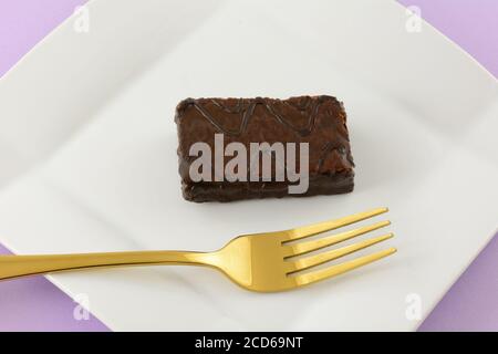 Schokolade überzogene Schokoladenkuchen Dessert auf weißen Snack-Teller mit Goldene Gabel Stockfoto