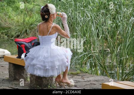 Frau in einem Hochzeitskleid und trinken eine Dose Bier in einem Park in Tokio, Japan. Stockfoto