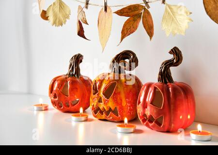 Halloween-Komposition mit Keramik Kürbisse Jack Laterne und Kerzen auf Tischwand Hintergrund. Heimtextilien Stockfoto