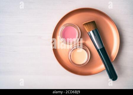 Make-up-Pinsel mit cremefarbenem Fundament und erröten Farben Schattierungen. Beauty Produkte Make-up Pinsel mit rosa und Rouge Farbgläser auf Edelstahl Stockfoto