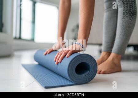 Yoga zu Hause Frau rollende Übungsmatte im Wohnzimmer Von Haus oder Wohnung Wohnung für Morgen Wellness Yoga Praxis Stockfoto