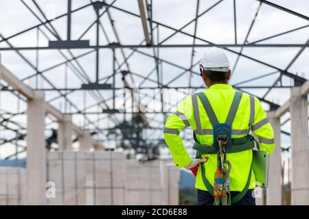 Asiatischer Ingenieur Techniker beobachten Bausteuerung in der Konstruktion von Dachkonstruktionen auf der Baustelle ein unvollendetes Bauprojekt Stockfoto