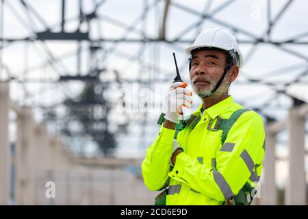 Asiatischer leitender Ingenieur Techniker, der die Bauüberwachung in der Konstruktion beobachtet Der Dachkonstruktionen auf der Baustelle eine unvollendete Konstruktion Stockfoto