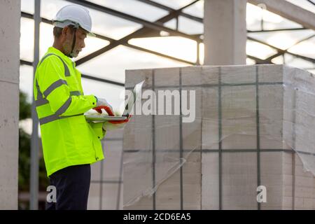 Asiatischer Ingenieur Techniker beobachten Bausteuerung in der Konstruktion von Dachkonstruktionen auf der Baustelle ein unvollendetes Bauprojekt Stockfoto