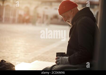 Reifer Bettler Mann schaut hoffentlich auf rostigen leeren Glas, warten auf Geld Hilfe. Armut, Hunger-Konzept Stockfoto