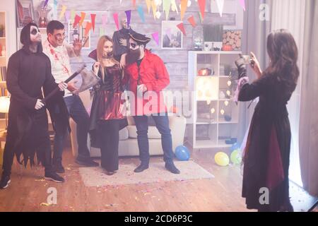 Rückansicht der Hexe, die Fotos von gruseligen Gruppe von Menschen auf halloween-Party. Stockfoto