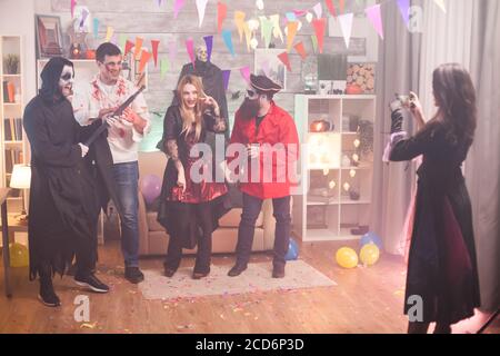 Rückansicht der Hexe, die Fotos von Sensenmann und seinen Freunden auf der halloween-Party. Stockfoto