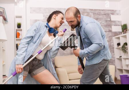 Frau, die auf dem Mopp singt, während sie das Haus putzt. Stockfoto