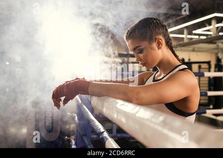 Müde kaukasische Frau Boxer stehen am Zaun gelehnt, nach erfolgreichem Training im Ring. Sportkonzept Stockfoto