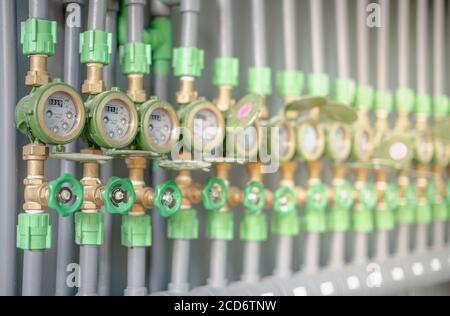 Reihe von Industrierohrleitungen und Armaturen mit grünen Rädern auf Graue Wand zur Überprüfung des Standardwasserstands in Der Schlafsaal für überprüfen Sie den Preis Stockfoto