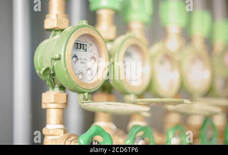 Reihe von industriellen Rohrleitungen und Ventile mit grünen Rädern auf graue Wand für die Überprüfung der Standard-Wasserstand im Schlafsaal für den Preis befindet. Stockfoto