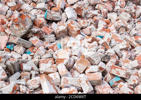 Haufen zerbrochener roter Steine auf der Baustelle, Abfall. Abstrakte Steinstruktur, Felsenhintergrund Stockfoto
