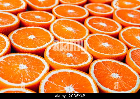 Rote Orangen oder Grapefruits werden auf schwarzem Hintergrund halbiert. Stockfoto
