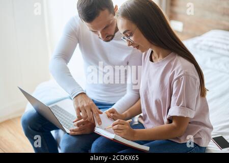 Toung angenehme Frau in optischen Spektren mit langen schönen Haaren, diskutieren Pläne für den Urlaub zusammen mit jungen Freund, Notiz Buch auf Stockfoto