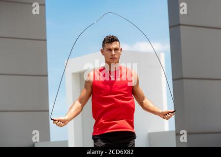 Schöner kaukasischer Athlet tun Morgen Outdoor-Übung springen Seil auf Dach des Gebäudes Stockfoto