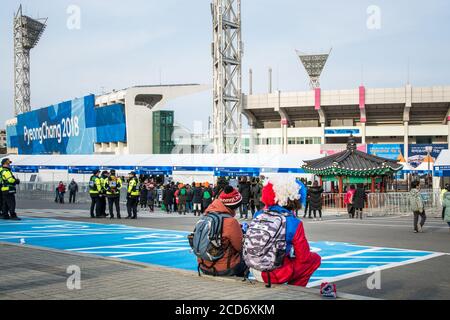Gangneung, Gangwon Provinz, Südkorea - ausländisches Touristenpaar sitzt auf der Straße nach dem Spiel im Olympiapark. Olympische Winterspiele 2018 In Pyeongchang. Stockfoto
