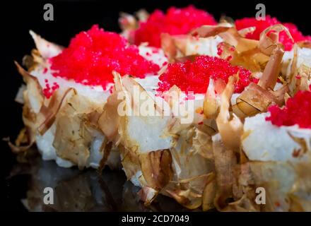 Sushi-Rollen mit Thunfisch oder Lachs Späne auf schwarzem Hintergrund. Stockfoto