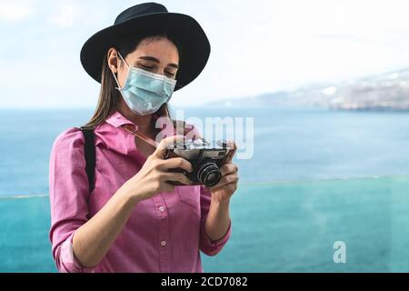 Junge Reisende Frau fotografieren mit alten Vintage-Kamera - glücklich Mädchen tragen Gesicht chirurgische Maske Erkundung neuer touristischen Destinationen Stockfoto