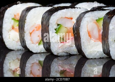 Sushi rollt Futo Maki auf schwarzem Hintergrund. Stockfoto