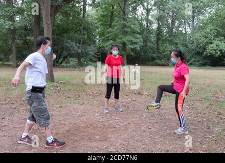 3 chinesische Amerikaner in chirurgischen Masken spielen Jianzi, in einem Park in Flushing, Queens, New York City. Stockfoto