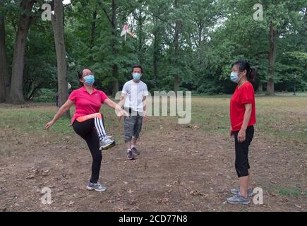 3 chinesische Amerikaner in chirurgischen Masken spielen Jianzi, in einem Park in Flushing, Queens, New York City. Stockfoto