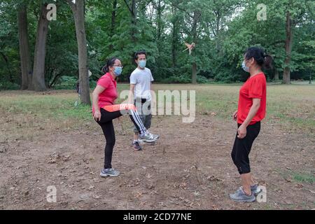 3 chinesische Amerikaner in chirurgischen Masken spielen Jianzi, in einem Park in Flushing, Queens, New York City. Stockfoto