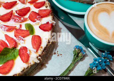 Appetitlich hausgemachter Käsekuchen mit Bio-Erdbeeren, Tasse Kaffee und Messer, Layout Stockfoto