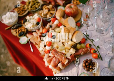 Eine Nahaufnahme eines Holzschneidebretts mit Fleisch- und Käseschnitten, Brot und Kirschtomaten auf einem langen Spieß. Stockfoto