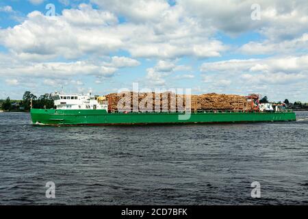 Das Schiff trägt Holzstämme entlang des Flusses. Stockfoto