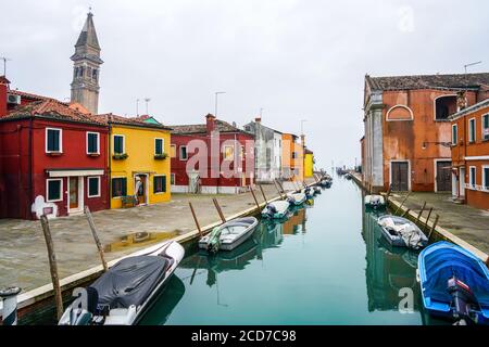 Schöner Kanal in Burano mit den typischen bunten Häusern und dem schiefen campanile (Glockenturm) der Kirche San Martino. Stockfoto