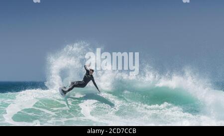 Ein Panoramabild spektakulärer Surfaktion, während ein Surfer eine Welle am Fistral in Newquay in Cornwall reitet. Stockfoto