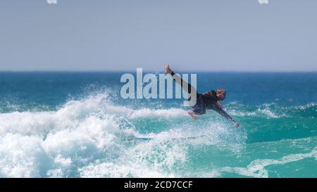 Ein Panoramablick auf wilde spektakuläre Action, während ein Surfer im Fistral in Newquay in Cornwall auswischt. Stockfoto