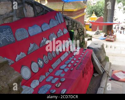 Ein Gebetsstein mit tibetischen Mantras Display in der roten Kleidung zum Verkauf in der Straße von Kathmandu, Nepal geschnitzt. Stockfoto