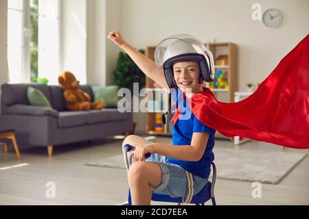 Superhelden-Kind. Kinderkostüm. Kinderzimmer. Kind Junge in roten Umhang und Superhelden Helm spielt in Kinderzimmer. Stockfoto