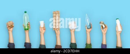 Hände mit verschiedenen Müll, Kunststoff, Metall, Glas und Papier auf einem blauen Hintergrund. Stockfoto