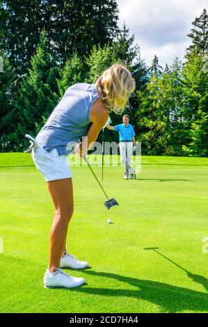 Mann und Frau Golf spielen auf einem schönen Parklandschaft an einem sonnigen Tag im Sommer. Stockfoto