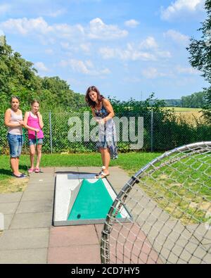 Frau mit Kindern spielt Minigolf an sonnigen Tagen Stockfoto