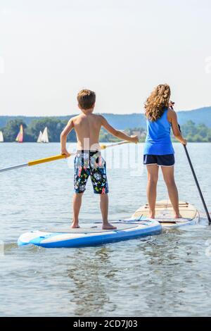 Kinder beim Stand Up Paddeln auf dem See Stockfoto