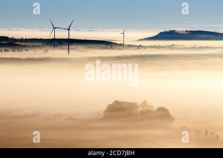Morgennebel über einer Agrarlandschaft mit Windturbinen Stockfoto