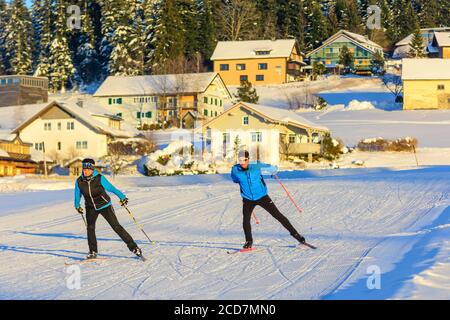 Zwei Skifahrer machen am späten Winternachmittag eine Skating-Übung In der Nähe eines Dorfes Stockfoto