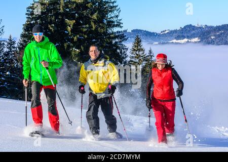 Eine Gruppe von gut gelaunten Menschen, die sich einem Schneeschuh Wanderung in der winterlichen Natur an einem kalten, sonnigen Tag Stockfoto