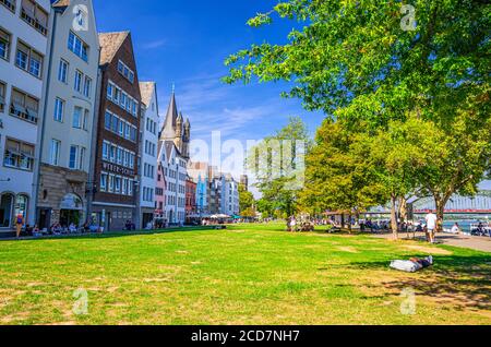 Köln, 23. August 2019: Typisch deutsche Häuser und Gebäude und grüne Rasenfläche mit Bäumen in der Nähe der Rheinpromenade in der Altstadt, Menschen Touristen, die eine Pause Stockfoto