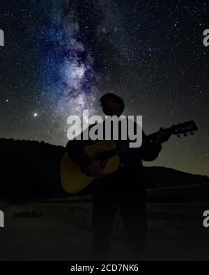 Teenager spielt Gitarre unter der Milchstraße bei Cherry Springs State Park Galaxie Sterne - Astrofotografie des Nachthimmels Dunkler Himmel & Sonnensystem Stockfoto