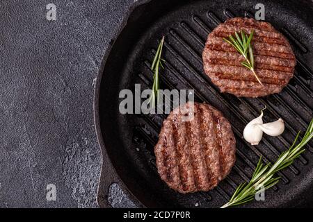 Gebratenes Schnitzel für Burger mit Gewürzen auf Grillpfanne, Draufsicht, Kopierraum. Stockfoto