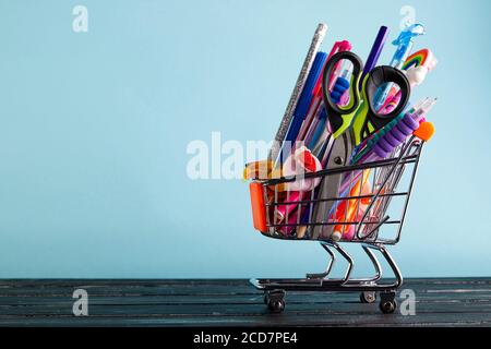 Banner von Warenkorb mit Schulbedarf auf blauem Hintergrund mit Kopierplatz. Zurück zur Schule Konzept Stockfoto