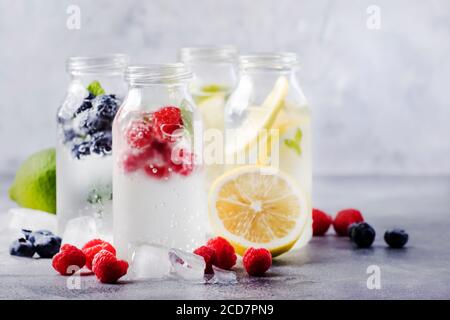 Sommergetränke. Beeren, Früchte und Zitrusfrüchte alkoholfreie erfrischende eiskalte Getränke und Cocktails in Glasflaschen auf weißem Hintergrund Stockfoto