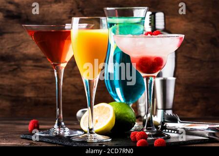 Farbenfrohe Sommercocktails. Kalte alkoholische Getränke und Getränke: mimosa, Cosmopolitan, Himbeere margarita und blau hawaii auf Holztisch Hintergrund w Stockfoto